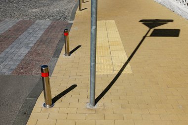 Şehir yaya geçidi, tuğlalı ve metal direkli cadde. Parlak güneşli bir gün