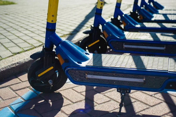 Parking E-scooters, Eco friendly mobility concept of sharing transportation with Electric Scooter. Summer sunny day, shadows on the street