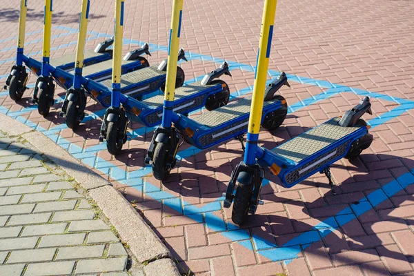 Parking E-scooters, Eco friendly mobility concept of sharing transportation with Electric Scooter. Summer sunny day, shadows on the street