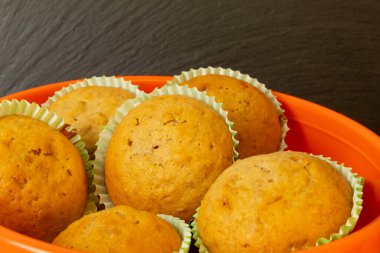 Turuncu tabakta bir sürü kek, karanlık bir arka planda yakın çekim. Hamur işleri kahvaltı için çok lezzetli..