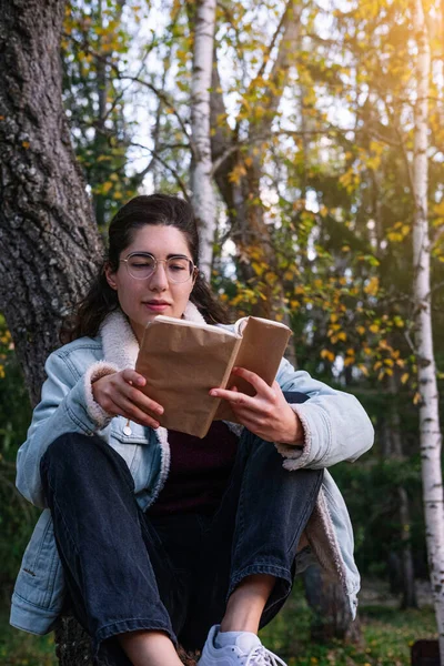 Ung Kvinna Med Glasögon Läser Bok Som Sitter Trädgren Läsbegrepp — Stockfoto