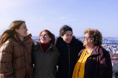 Farklı yaşlarda bir grup kadın birbirlerinin kollarında gülüyor. Kadın kavramı. Feminizm kavramı.