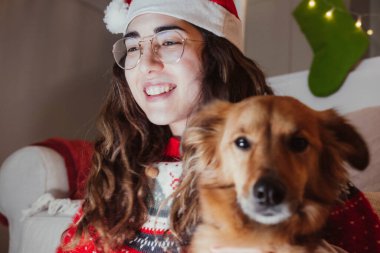 Köpeğiyle Noel kıyafetleri giymiş genç bir kadının portresi. Noel konsepti.