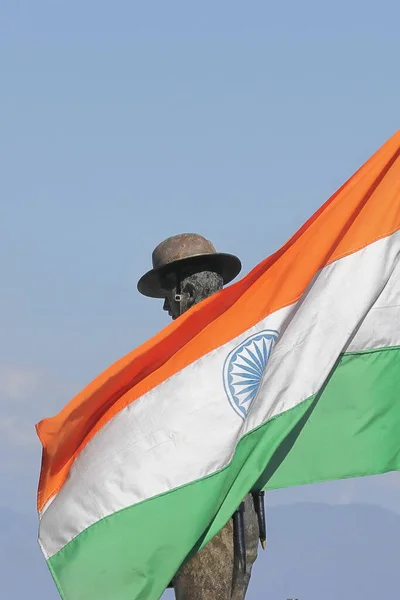 tri colour indian national flag is waving against blue sky with a statue of indian army at batasia loop, darjeeling, west bengal in india