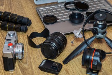Dizüstü bilgisayarı olan çeşitli fotoğraf cihazları, masada cep telefonu..
