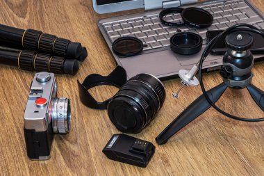 Dizüstü bilgisayarı olan çeşitli fotoğraf cihazları, masada cep telefonu..