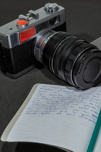 Bir dizüstü bilgisayar, eski bir kamera ve bir not defteri bileşimi