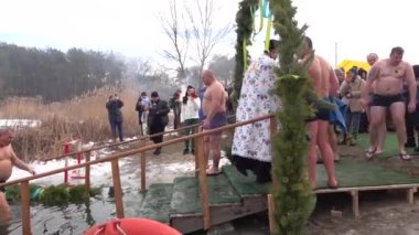 Kiev, Ukrayna 19 Ocak 2021 'de rahip, Rus vaftiz töreninin olduğu gün insanların kışın delikte yıkanması için suyu kutsadı.