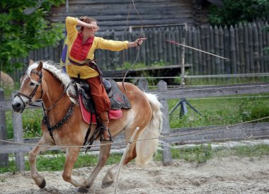 Kiev, Ukraine June 19, 2021: Horse rider shoots a bow at a target in an old outfit - show in the entertainment complex Kievskaya Rus