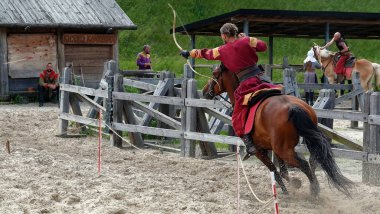 Kiev, Ukraine June 19, 2021: Horse rider shoots a bow at a target in an old outfit - show in the entertainment complex Kievskaya Rus