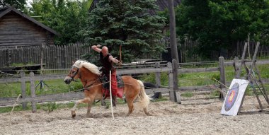 Kiev, Ukraine June 19, 2021: Horse rider shoots a bow at a target in an old outfit - show in the entertainment complex Kievskaya Rus