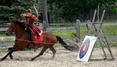 Kiev, Ukraine June 19, 2021: Horse rider shoots a bow at a target in an old outfit - show in the entertainment complex Kievskaya Rus