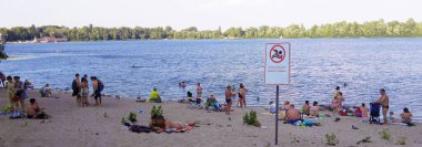 Kiev, Ukraine June 24, 2019: Beach holidays in the city on the river, people bathe although the plate is on which it says that swimming is prohibited