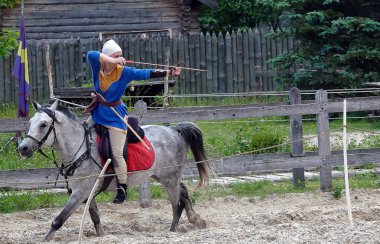 Kiev, Ukraine June 19, 2021: Horse rider shoots a bow at a target in an old outfit - show in the entertainment complex Kievskaya Rus