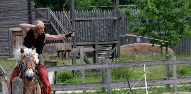 Kiev, Ukraine June 19, 2021: Horse rider shoots a bow at a target in an old outfit - show in the entertainment complex Kievskaya Rus