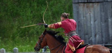 Kiev, Ukraine June 19, 2021: Horse rider shoots a bow at a target in an old outfit - show in the entertainment complex Kievskaya Rus