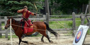 Kiev, Ukraine June 19, 2021: Horse rider shoots a bow at a target in an old outfit - show in the entertainment complex Kievskaya Rus