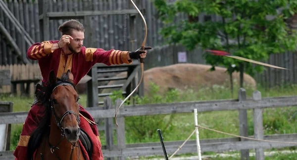 Kiev, Ukraine June 19, 2021: Horse rider shoots a bow at a target in an old outfit - show in the entertainment complex Kievskaya Rus