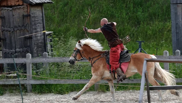 Kiev, Ukraine June 19, 2021: Horse rider shoots a bow at a target in an old outfit - show in the entertainment complex Kievskaya Rus