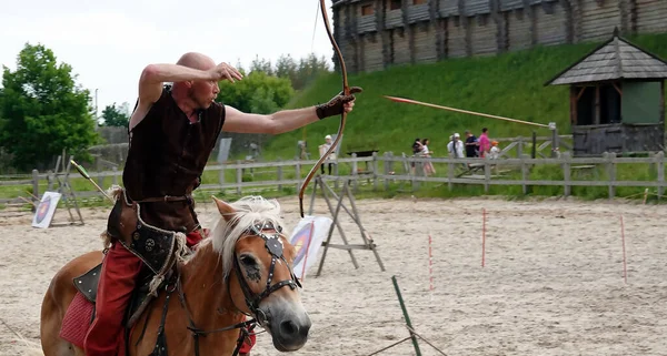 Kiev, Ukraine June 19, 2021: Horse rider shoots a bow at a target in an old outfit - show in the entertainment complex Kievskaya Rus