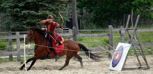 Kiev, Ukraine June 19, 2021: Horse rider shoots a bow at a target in an old outfit - show in the entertainment complex Kievskaya Rus