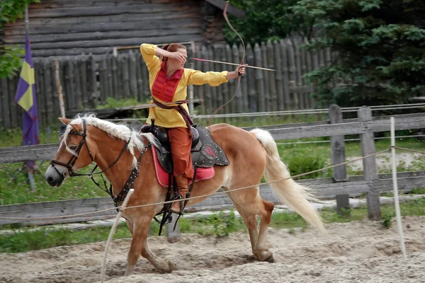 Kiev, Ukraine June 19, 2021: Horse rider shoots a bow at a target in an old outfit - show in the entertainment complex Kievskaya Rus