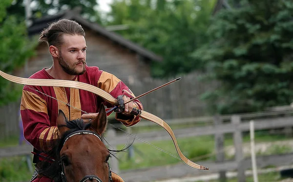 Kiev, Ukraine June 19, 2021: Horse rider shoots a bow at a target in an old outfit - show in the entertainment complex Kievskaya Rus