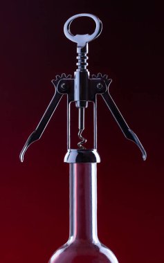A wine cork opener rests on the long neck of a wine bottle.