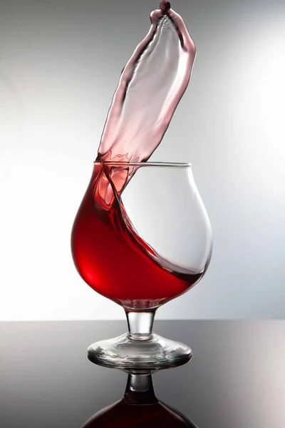Glass Red Drink Explodes Splashes Gray Background — Fotografia de Stock