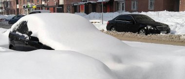 Cars in the city on the sidelines covered with snow