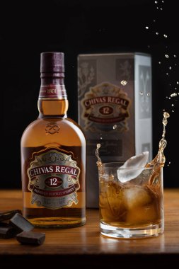 Chivas regal Scotch Whisky Stüdyo ürün fotoğrafçılığı. Buzlu viski bardağının stüdyo fotoğrafçılığı ve siyah arka planda bir kutu Chivas Regal..