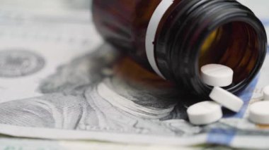 İçinde ilaç şişesi ve haplar olan 100 dolarlık banknotlar. Para ve ilaç endüstrisi arasındaki ilişkiye dair fikir.