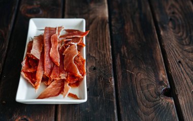 Kurutulmuş tavuk, ahşap bir tahtada tuz, biber, ketçap, ketçap parçalarıyla dilimlenmiş.