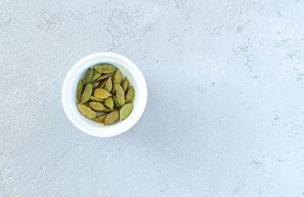 Cardamomo em uma placa branca, em um fundo cinza — Fotografia de Stock