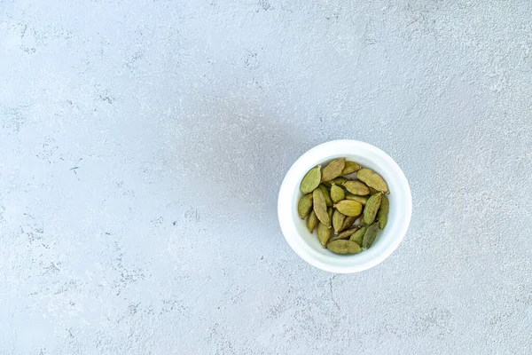 Cardamomo em uma placa branca, em um fundo cinza — Fotografia de Stock