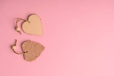 Top view of two wooden heart shaped decoration laying on pink background with copy space. Concept of love and relationship using for valentine day holiday