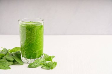 Yeşil doğal vejetaryen ıspanaklı smoothie ya da bir bardak dolusu yapraklı meyve suyu beyaz ahşap masada servis edilir. Sağlıklı beslenme ve sağlık konsepti. Kopyalama alanı olan resim