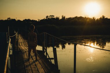 Asma köprüdeki çocuk gün batımıyla buluşuyor.