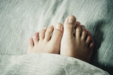 Ayaklar battaniyenin altında, yakın plan.