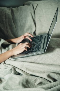 Yatakta dizüstü bilgisayarın arkasındaki adam.