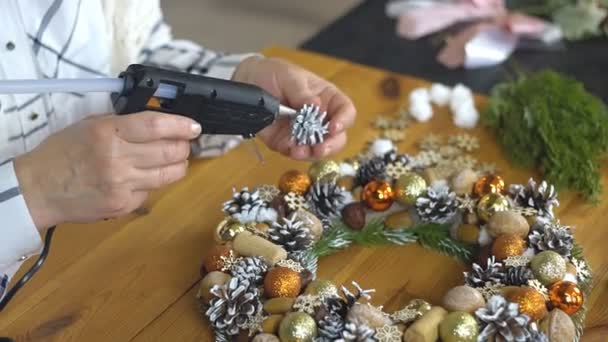 Närbild av kvinna händer dekorera julkransen med en inredning med hjälp av ett lim pistol. — Stockvideo