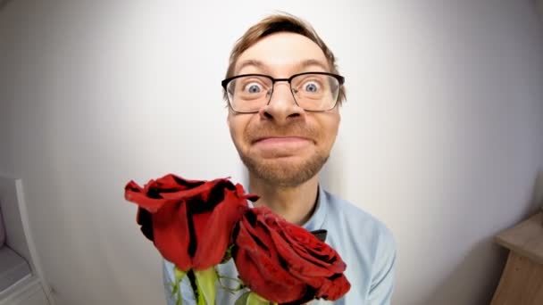 Rybie oko portret młodego męskiego nerda w okularach i eleganckim stroju z muszką trzymającą czerwoną różę i patrzącą w kamerę. Koncepcja Walentynek. — Wideo stockowe