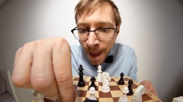 Fisheye portrait of crazy nerd chess player with glasses, looking at camera — Stockvideo