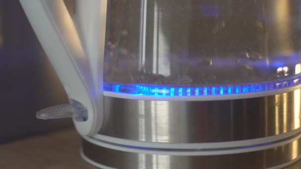 Крупный план электрического стеклянного чайника, кипящего воду для горячих напитков. Пузырьковая вода. — стоковое видео