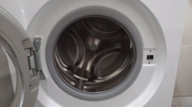 Kirli çamaşırları çamaşır makinesine koyan kızgın adama yaklaş..