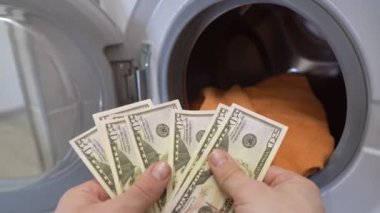 Adam çamaşır makinesine dolar koyuyor. Para Aklama Suçu Konsepti.