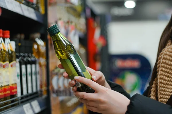Female hand choosing natural olive oil at store. Concept of healthy food, bio, vegetarian, diet. — стоковое фото