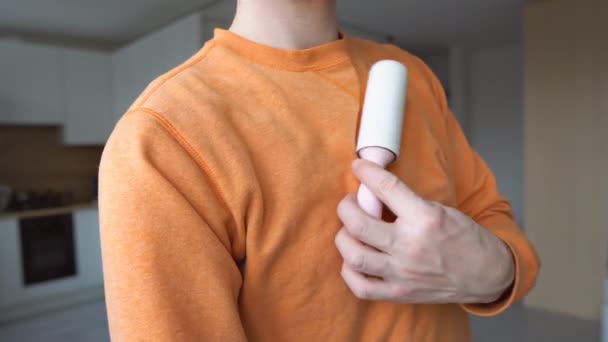 Man hand using adhesive sticky roller to clean clothes, close up. — Vídeo de Stock
