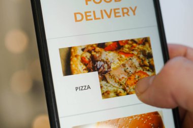 Ekranda uygulamalı akıllı telefon kullanarak erkek ellerini kapat. Pizzayı seçen genç adam.
