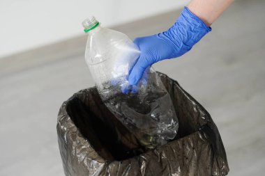 Lastik Eldiven Giyen Kadın Boş Plastik Şişeyi Çöp Kutusuna Fırlatıyor.